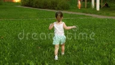夏天，快乐的孩子在草地上奔跑，在绿草上奔跑。 开朗的小女孩跑过田野。 幸福的概念